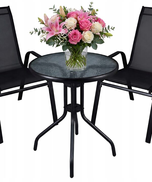 Round glass patio table with a vase of pink and white roses, flanked by two black mesh outdoor chairs.